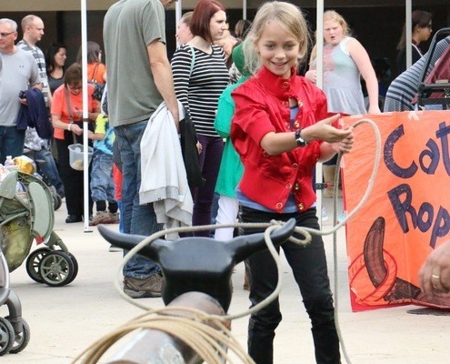 Student roping a bull statue at a Harvest Fair