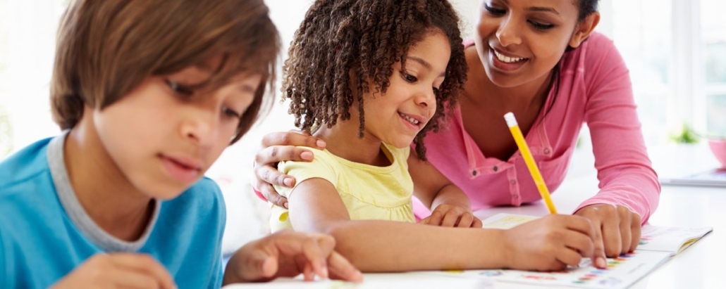 Mixed Race Mother Helping Mixed Race Children With Homework In Kitchen