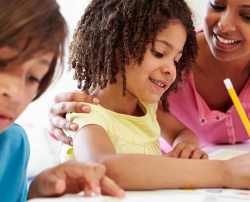Mixed Race Mother Helping Mixed Race Children With Homework In Kitchen