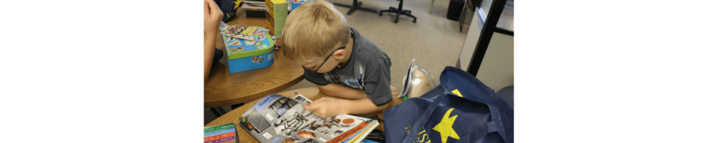 Kid reading a book with a Visions bag next to her