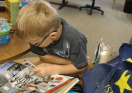 Kid reading a book with a Visions bag next to her