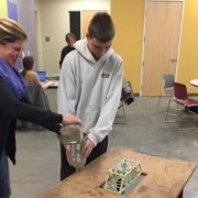 Image of student and teacher testing toothpick bridge with weight