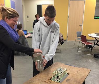 Image of student and teacher testing toothpick bridge with weight