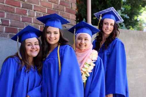 Four female graduates smiling at the camera on graduation day