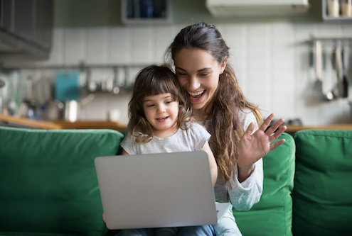 Happy mother and kid daughter waving hands looking at web camera using laptop for video call