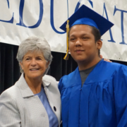 Summer grad posing on stage with Superintendent Jody Graf