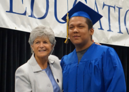 Summer grad posing on stage with Superintendent Jody Graf