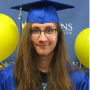 Male graduate smiling at the camera with cap and gown