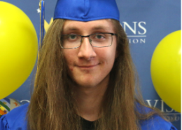 Male graduate smiling at the camera with cap and gown