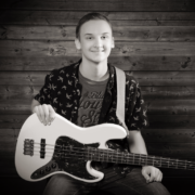 Male student smiling at the camera holding a guitar