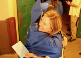 Grad in cap & gown hugging teacher