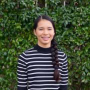 Bailey, female student stands in front of ivy covered wall