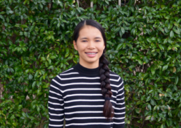 Bailey, female student stands in front of ivy covered wall