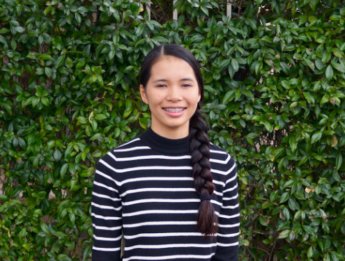 Bailey, female student stands in front of ivy covered wall