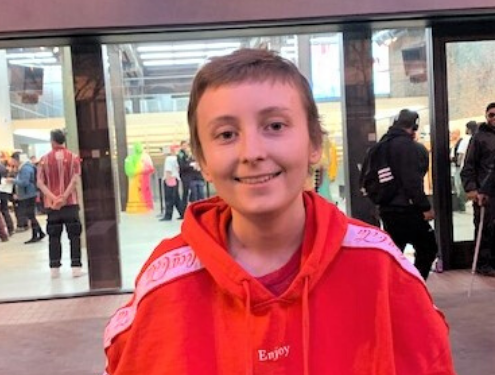 Independent study high school student, Talon B., smiles at the camera in a red sweatshirt