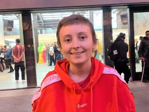 Independent study high school student, Talon B., smiles at the camera in a red sweatshirt