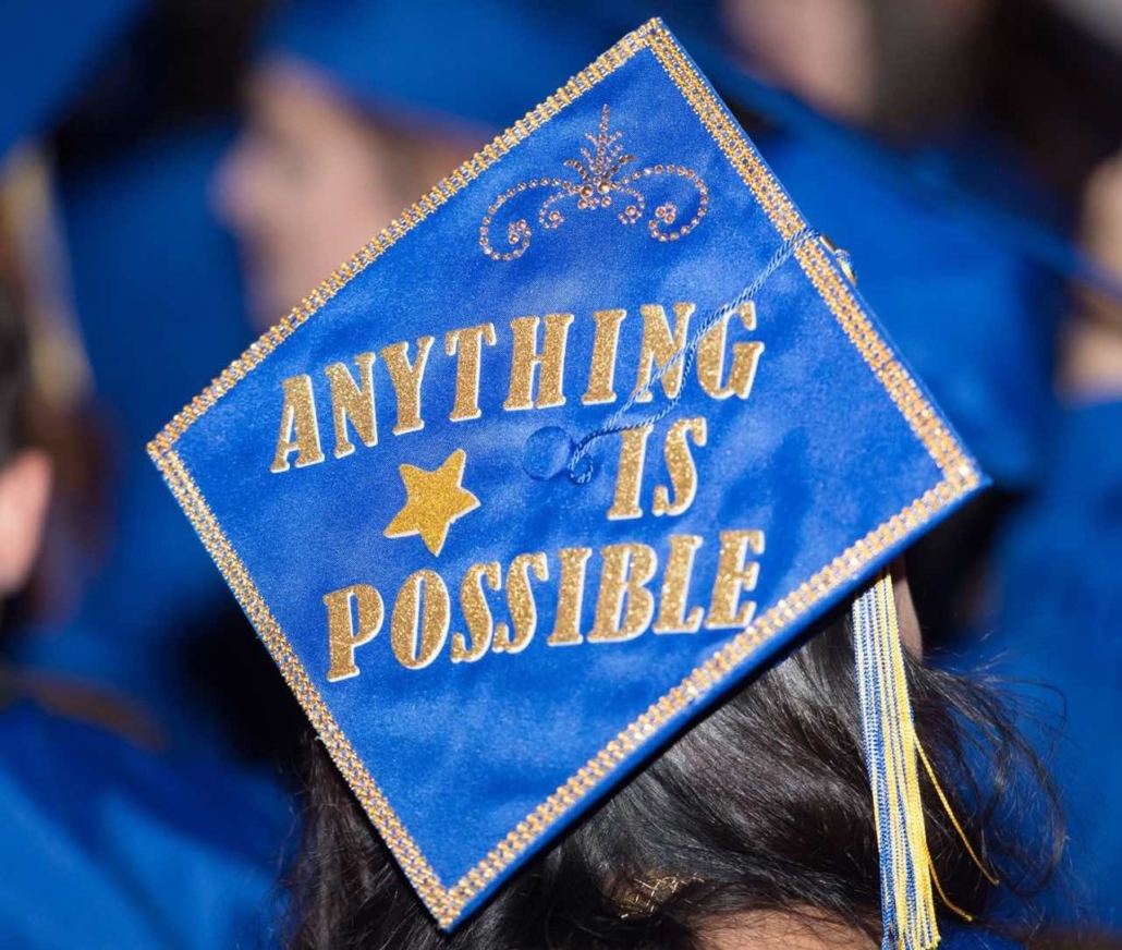 Blue Graduation Cap with Anything is possible spelled out in gold glitter letters