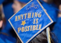 Blue Graduation Cap with Anything is possible spelled out in gold glitter letters