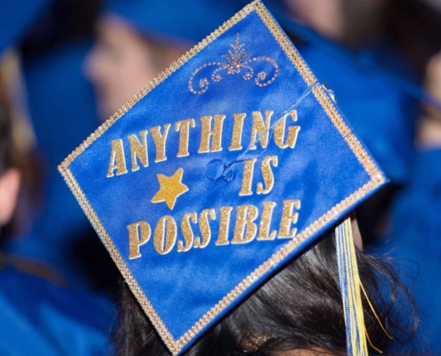 Blue Graduation Cap with Anything is possible spelled out in gold glitter letters