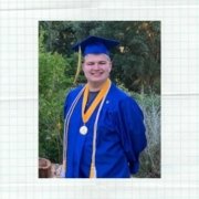 Male online high school graduate smiles at the camera wearing a blue cap and gown