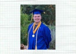 Male online high school graduate smiles at the camera wearing a blue cap and gown