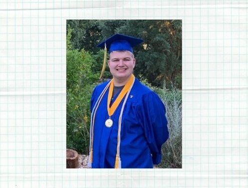 Male online high school graduate smiles at the camera wearing a blue cap and gown