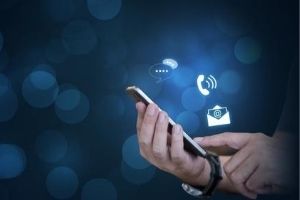Contact us imagery with business man holding cell phone with floating text message, phone and email icons