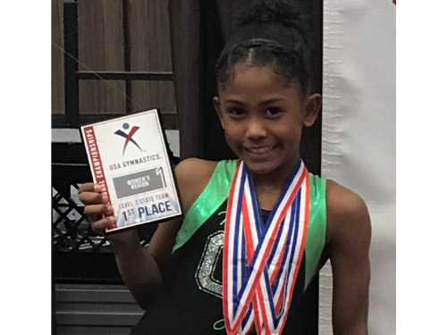 Tyler, African American 6th grader poses with Junior Olympic gymnastics award