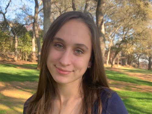 High school graduate smiles at the camera in a park