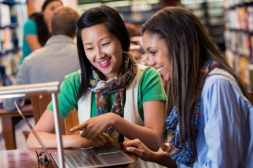 Happy school counselor and high school student reviewing information for college on laptop