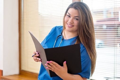 Happy female high school student learning about healthcare in career technical education program reading file
