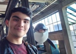 Smiling home school boy stands next to replica of a dolphin