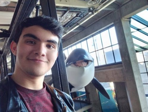 Smiling home school boy stands next to replica of a dolphin