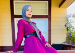 Female high school student in gray hijab sits on railing