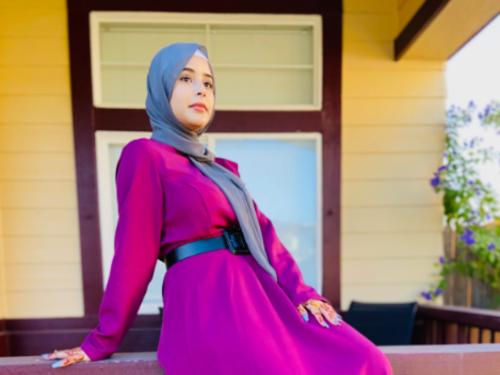 Female high school student in gray hijab sits on railing