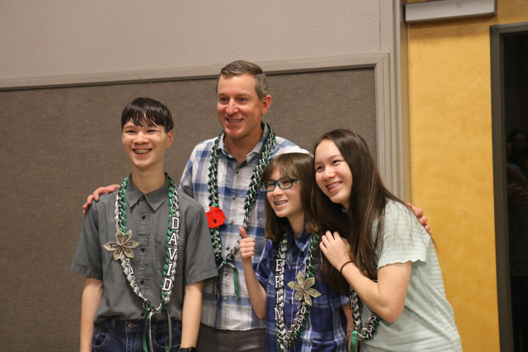 Dad smiles with his three children, two girls and one boy at 8th grade promotion