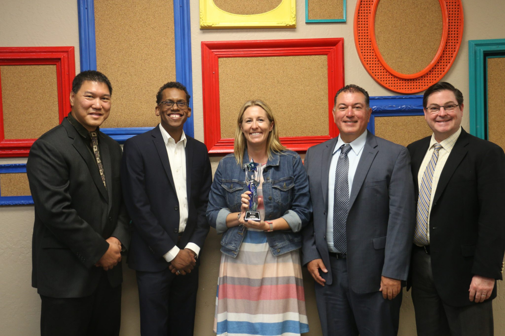 Visions board members and Superintendent pose in front of frame decorated wall to say goodbye to exiting female board member