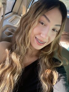 Smiling female teen with long hair takes selfie in her car