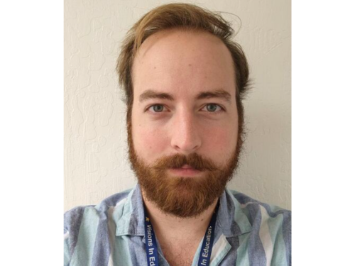 Wearing a light blue striped shirt, Nick Micheels poses for a selfie.