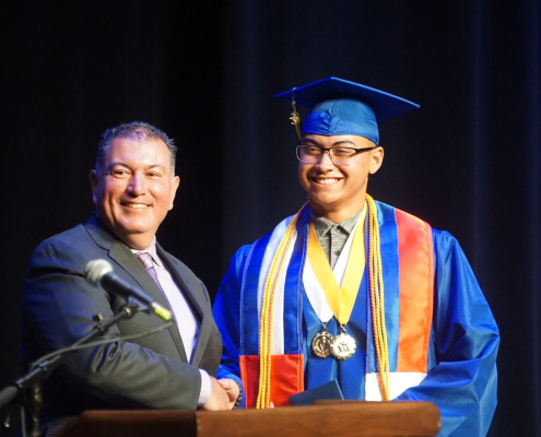 Male Superintendent poses with Filipino male graduate on staff at graduation