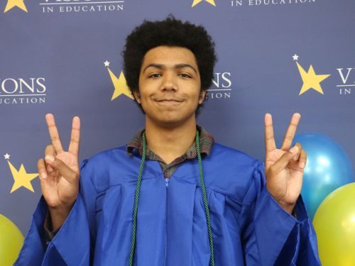 Lenny, eSports champ, Visions graduate and STS staff member gives the peace sign at high school graduation