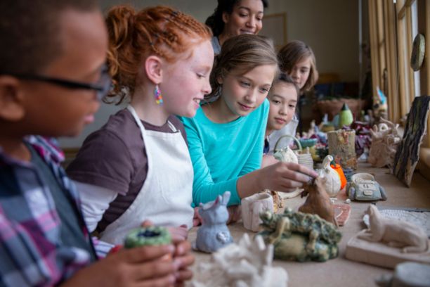 Teacher and group of home school students shaping clay figurines in art class