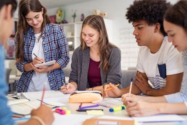 Happy team of high school girls and guys studying together and laughing