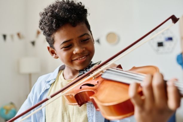 Smiling boy learning to play the violin
