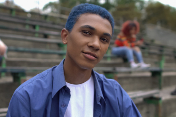 Male teen with blue hair smirking at the camera at high school
