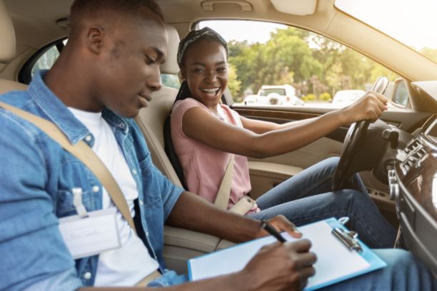 Smiling teen taking driving lessons from driver's ed teacher for enrichment