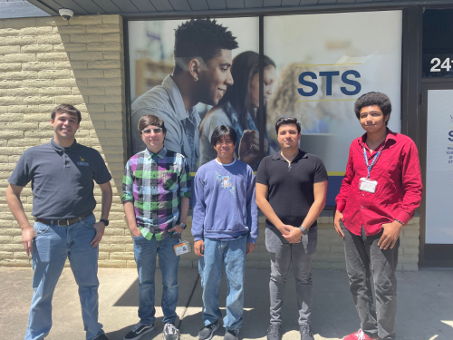 Five members of the STS team stand outside the STS building and smile for a picture.
