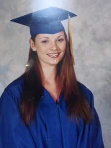 Girl in blue Visions graduation cap and gown smiles for her official graduation photo.