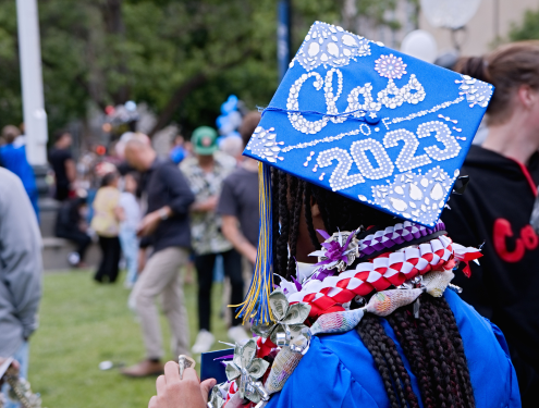 Photo taken from the back of a girl wearing a blue Visions graduation cap with "Class of 2023" written in rhinestones on the top.