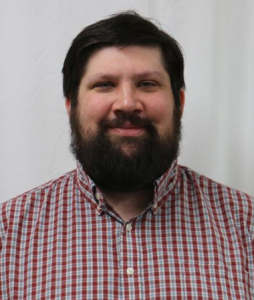 Michael Miller (staff member) in a red plaid shirt smiles for a staff photo.